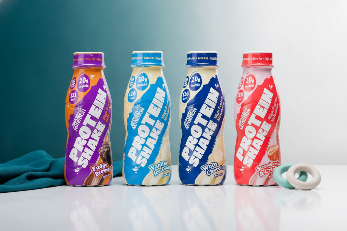 Several Applied Nutrition Protein Shakes in a clean, modern studio setting with teal and white accents.
